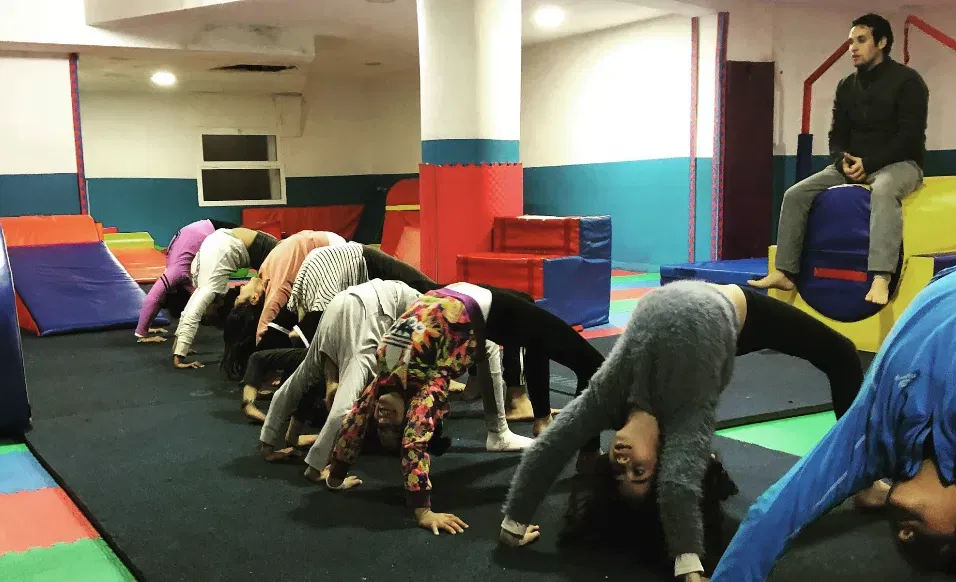 Coach de gymnastique KidiClub observant des enfants pendant un étirement