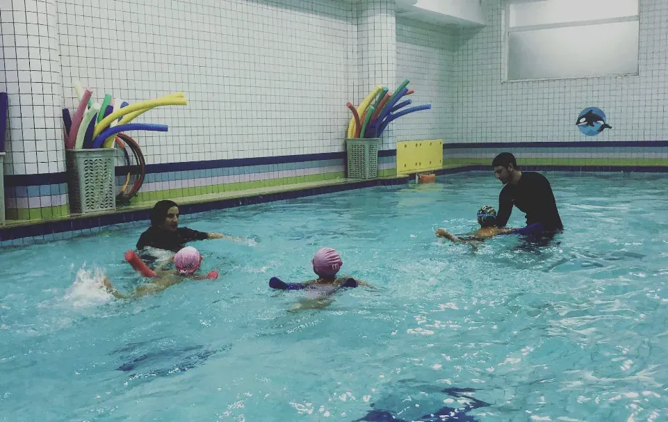 Enfants avec frites de piscine et coachs pendant un cours de natation